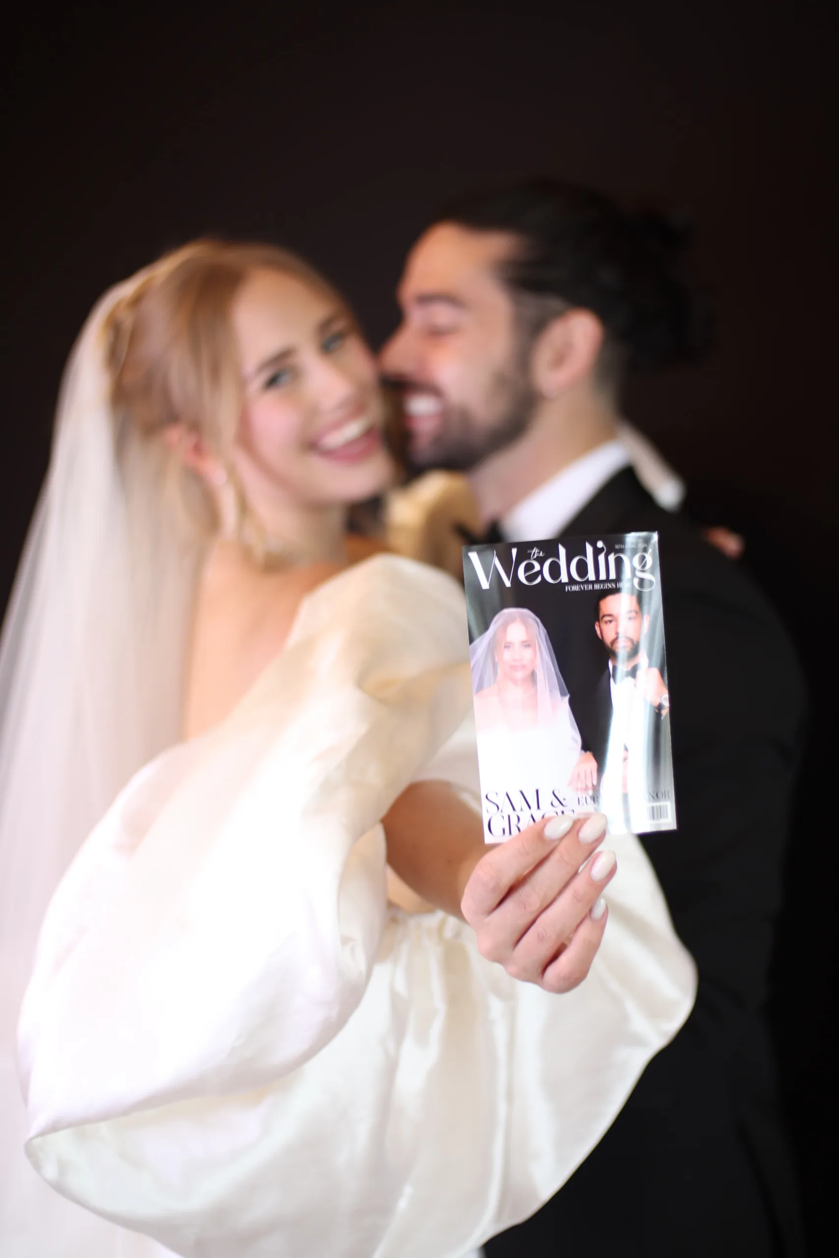 A bride and groom holding their printed photo from the Magazine Photo Booth Experience at Euridge Manor